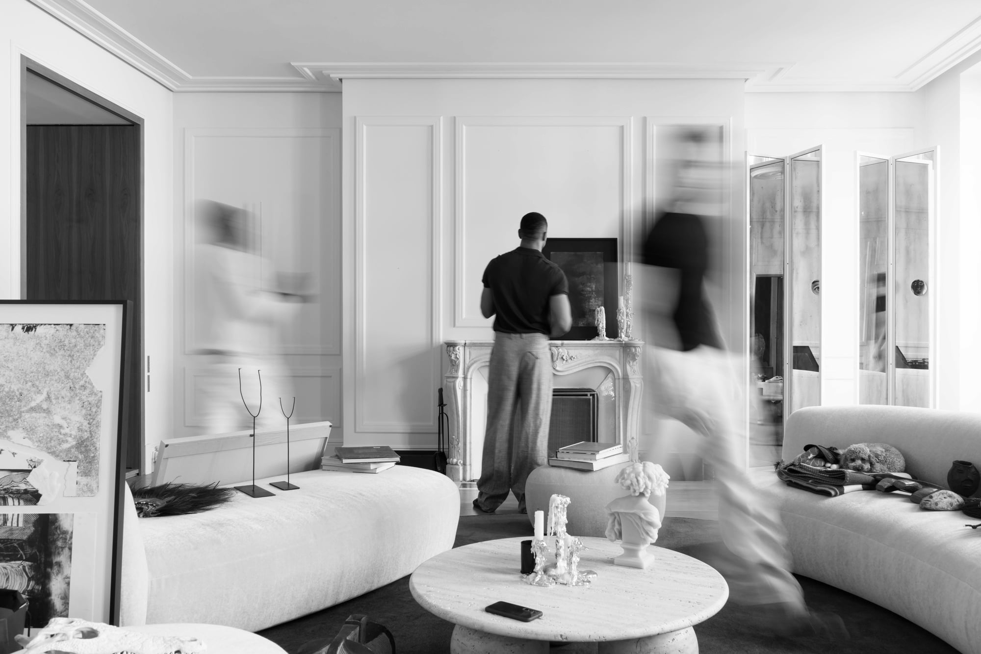 Behind the scenes during an interior photography shoot with the interior designer and two blurred figures arranging the space.