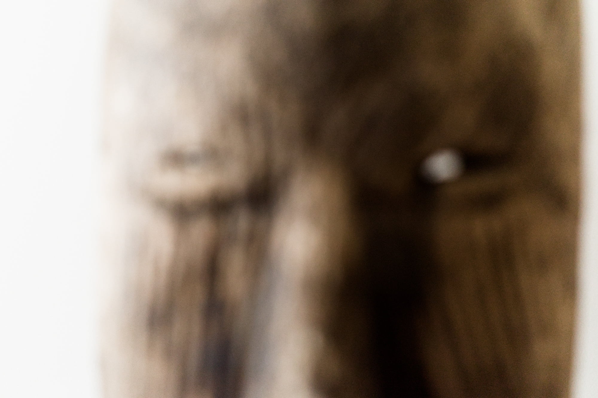 Soft-focus close-up of an African mask emphasizing its eyes and weathered surface.