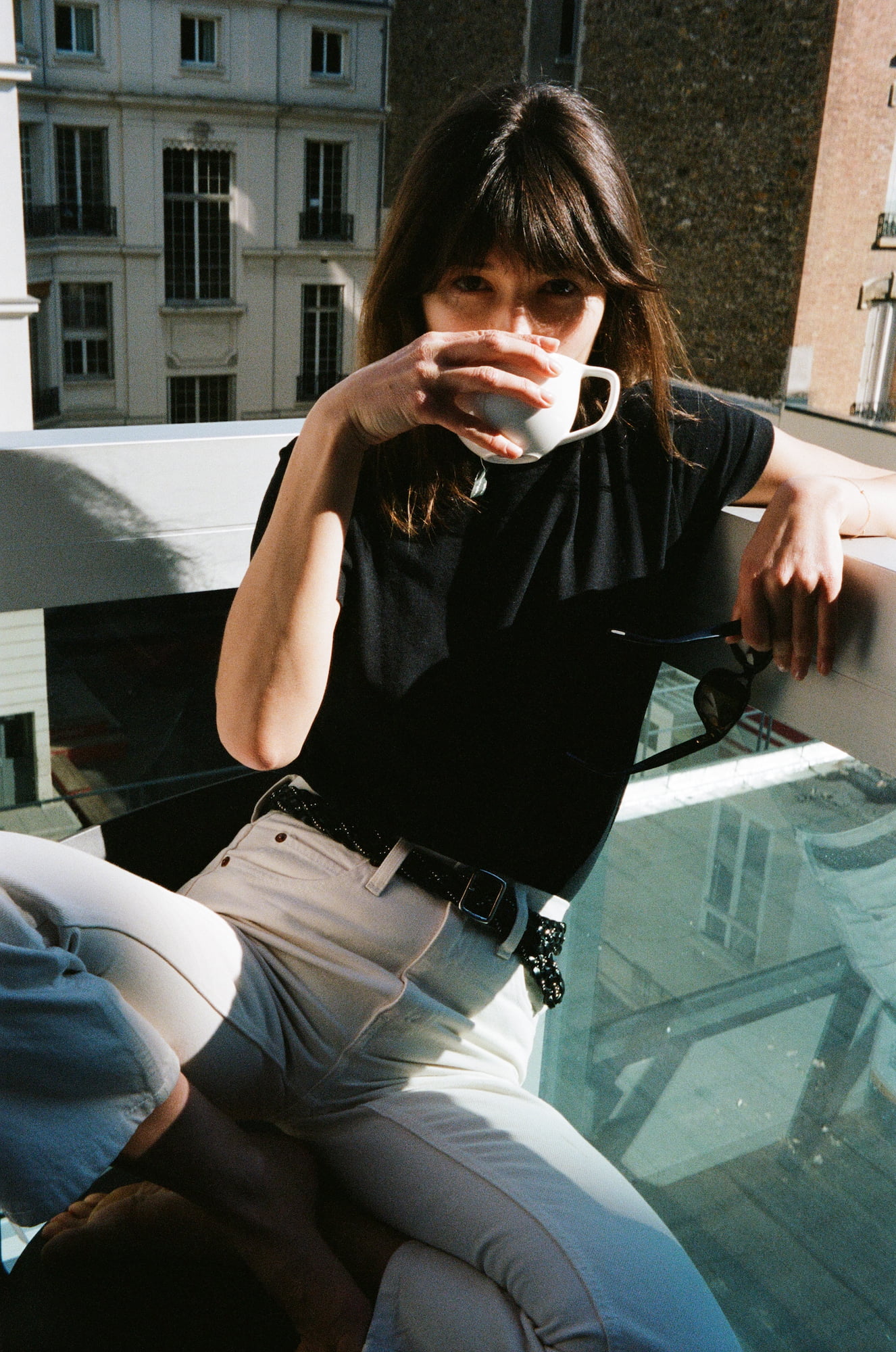 Ariadna drinking coffee on her sunlit balcony in Paris