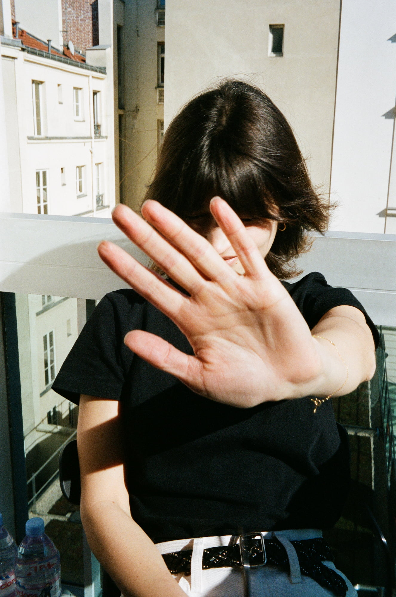 Ariadna raising her hand toward the camera on her balcony in Paris
