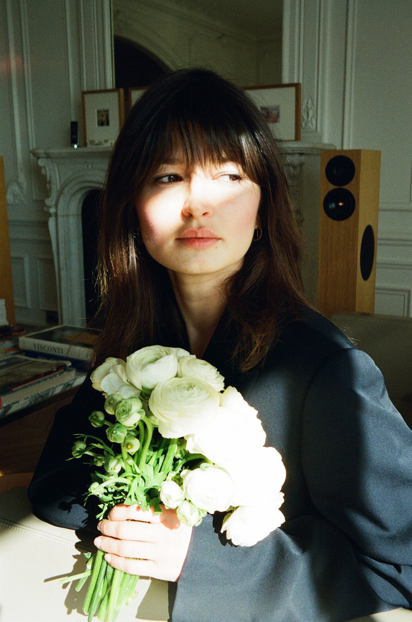 Ariadna holding white flowers in sunlight at an apartment in Invalides, Paris