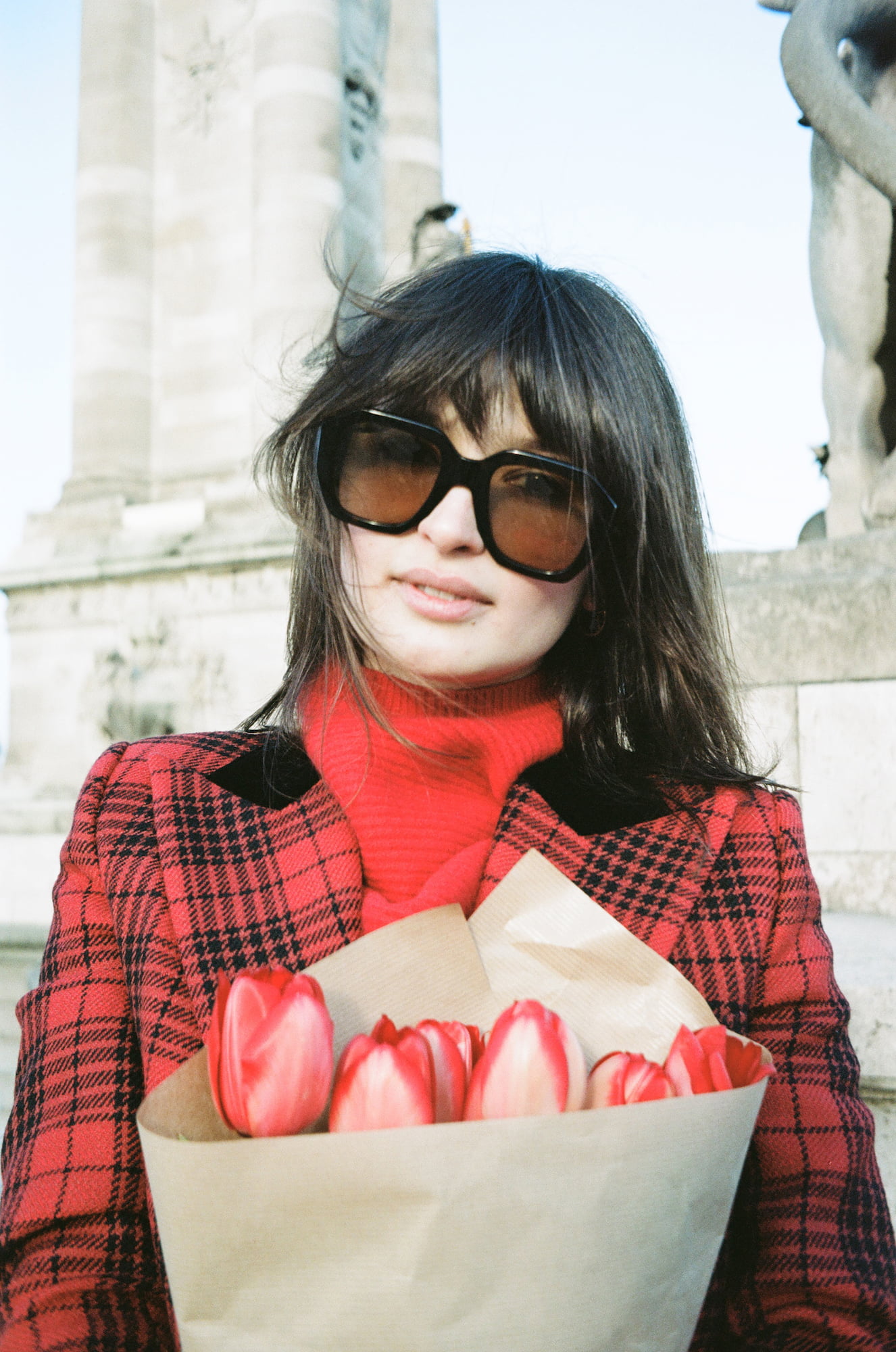 Ariadna holding red tulips near the Pont Alexandre III in Paris