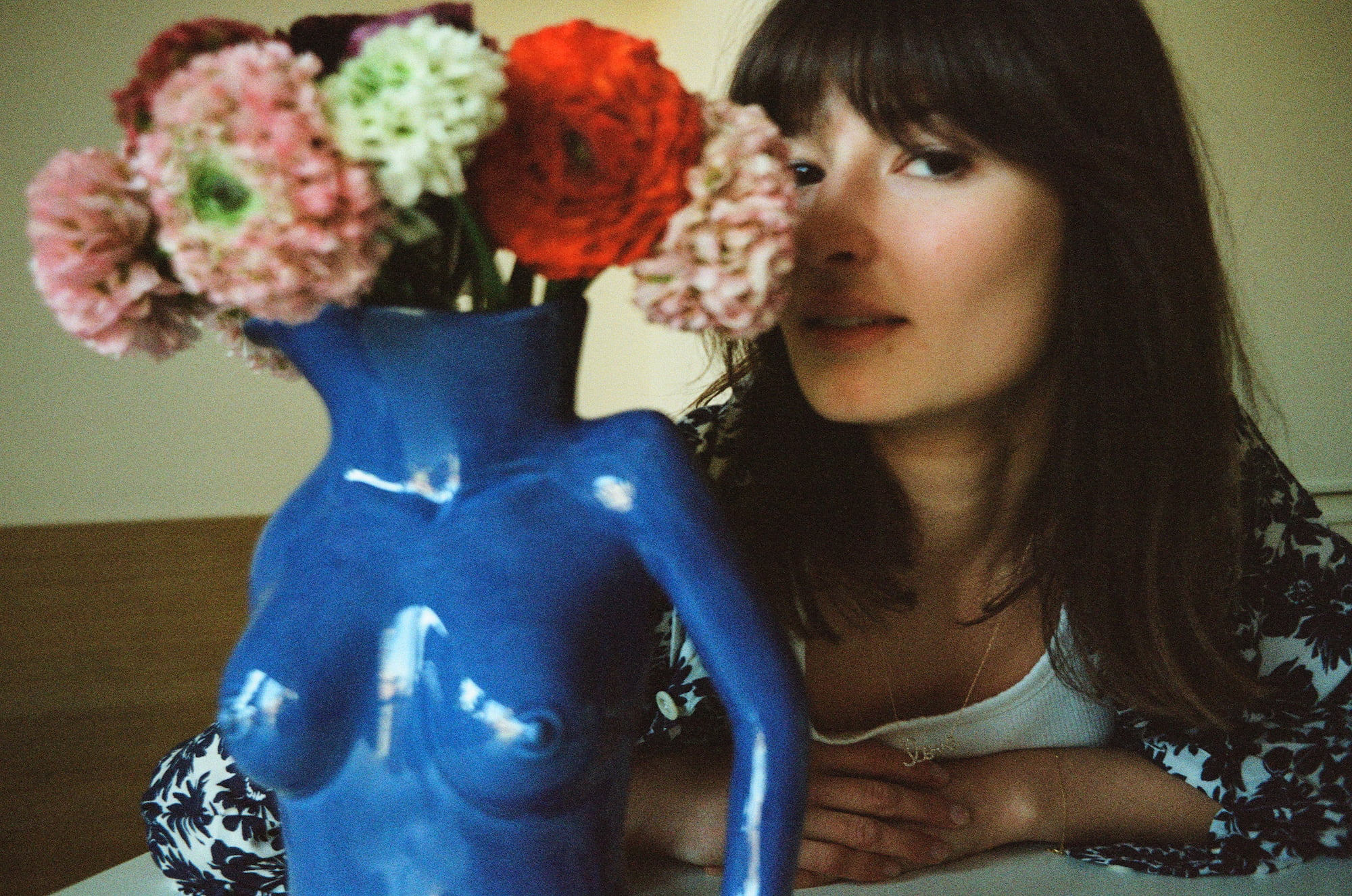 Ariadna partly hidden behind flowers in a blue vase at her home in Paris
