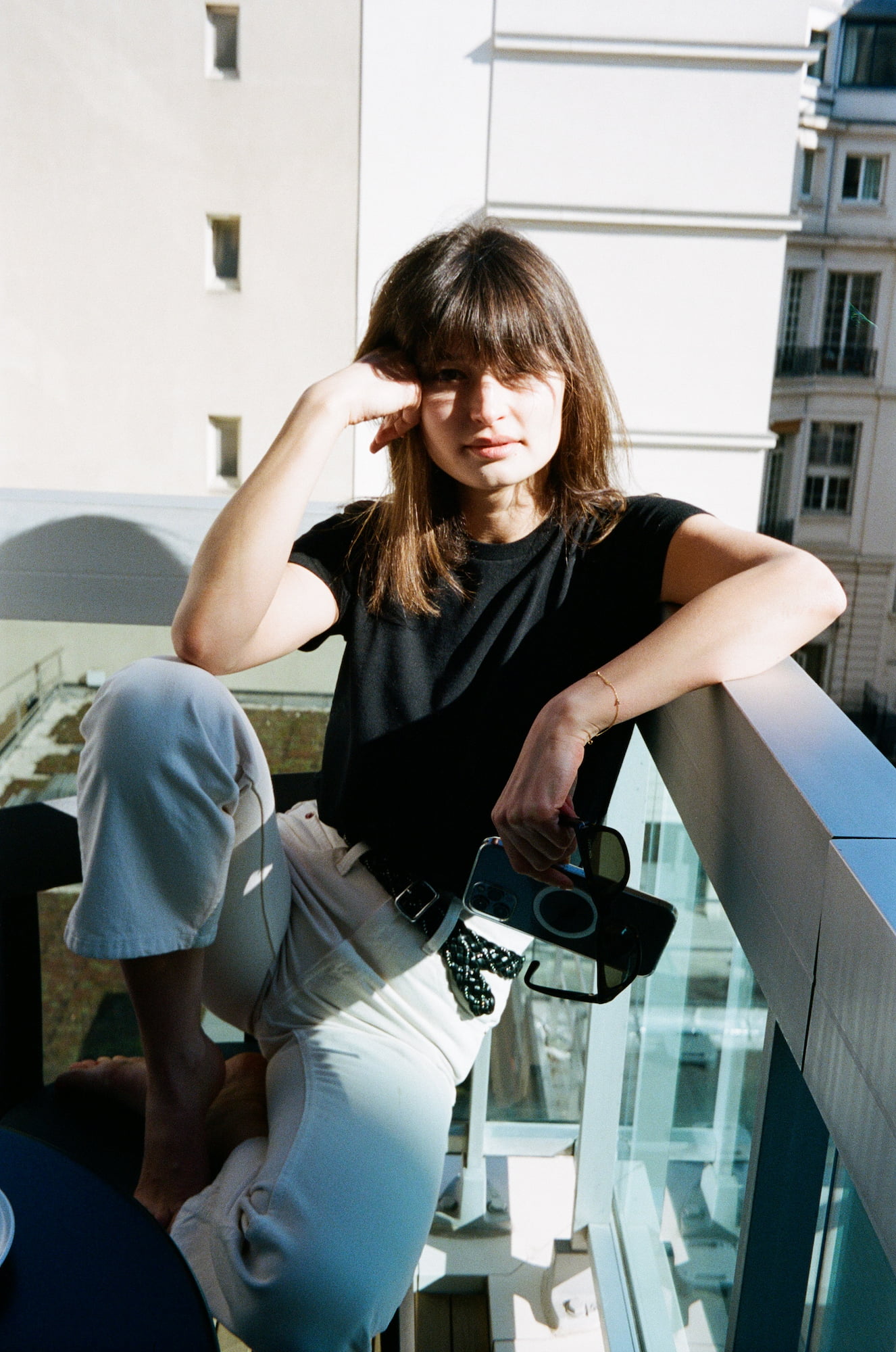 Ariadna seated on her balcony holding sunglasses in Paris
