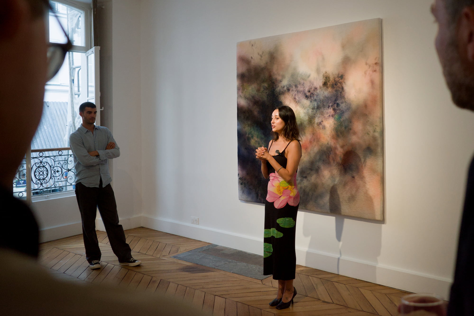 Samia Bahemmouche speaking to guests in front of a large abstract painting during Arty House in Paris