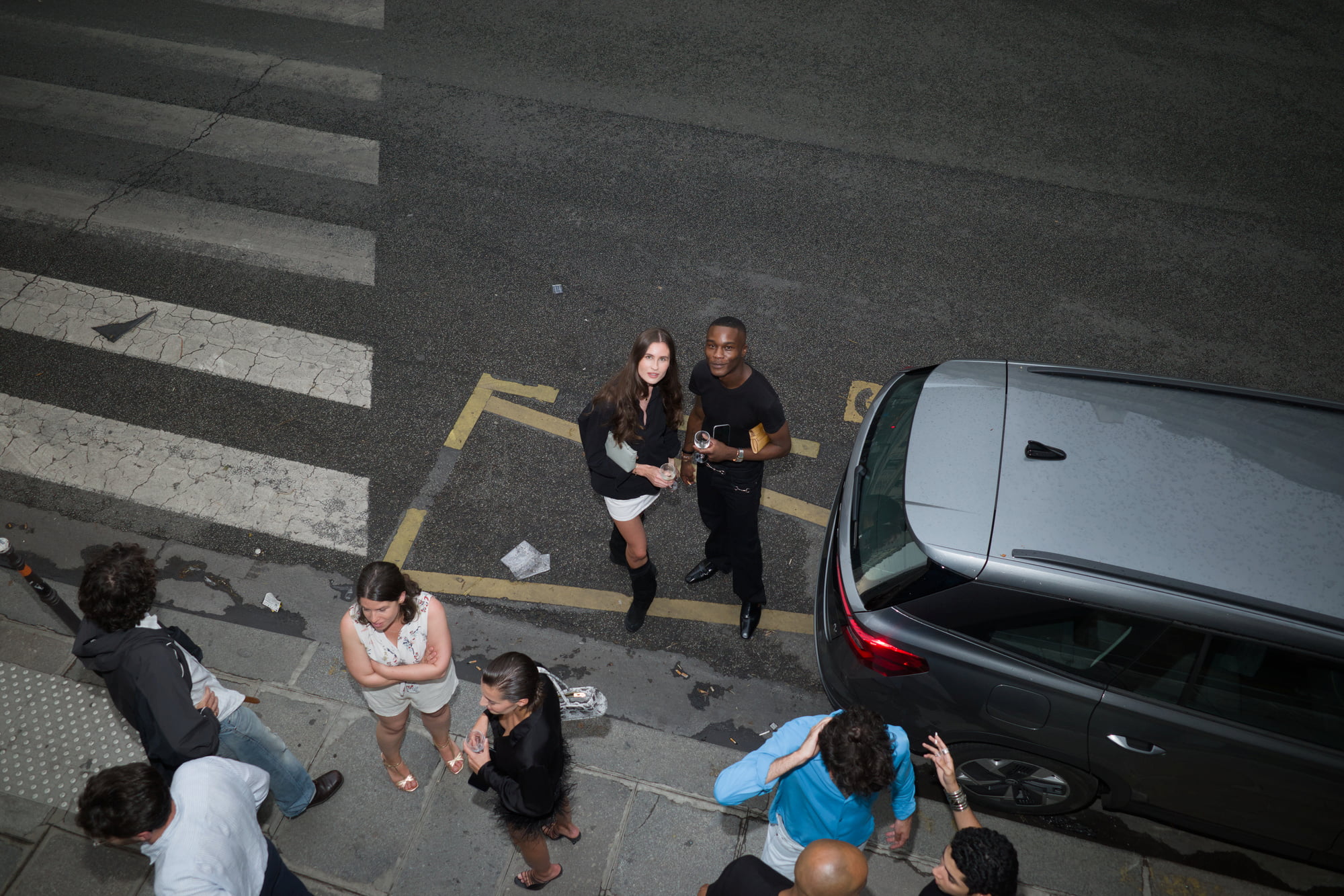 Randy Gowon and Amélie Carrara outside the gallery looking up toward the camera from the street