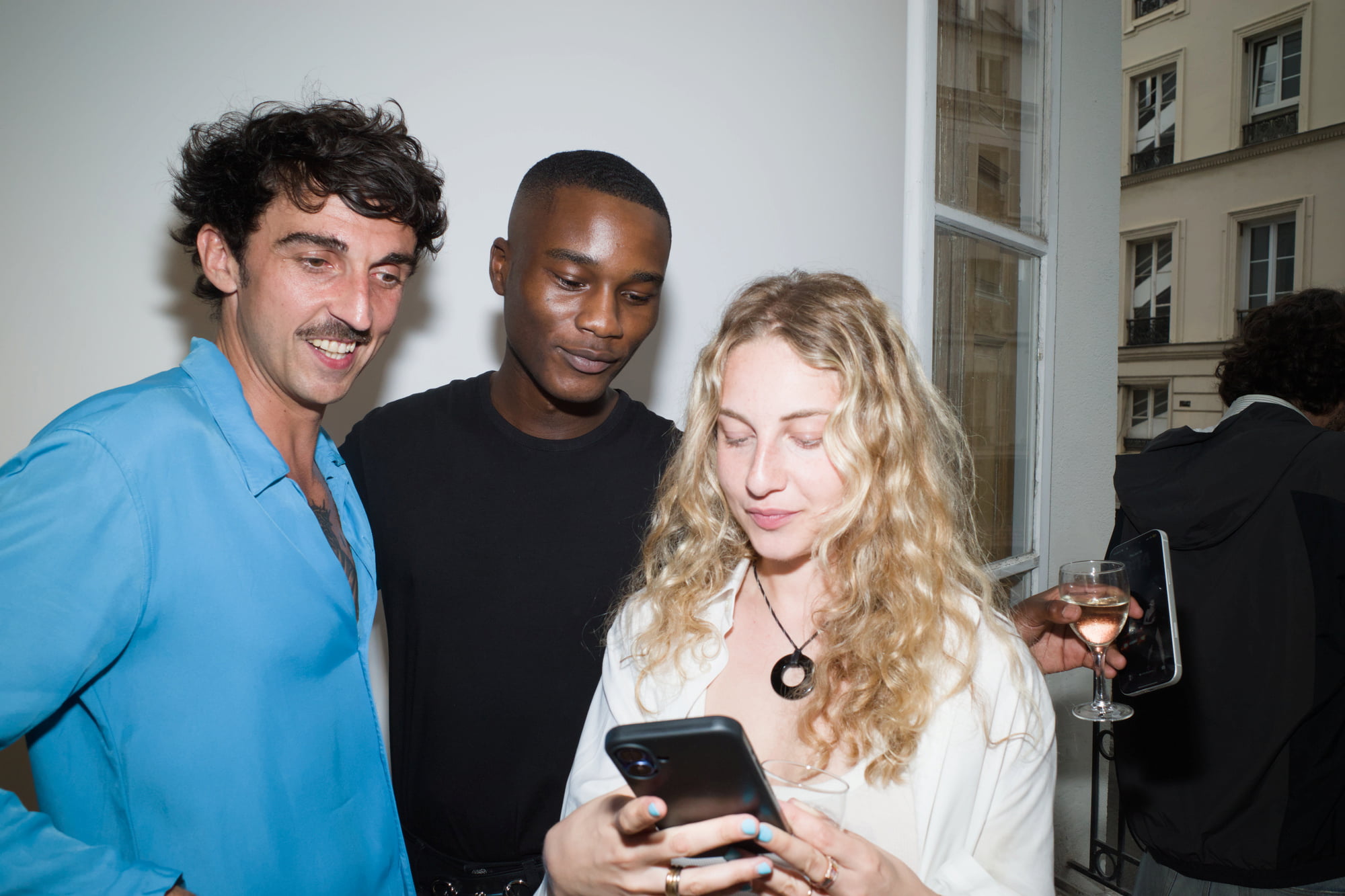 Randy Gowon and Salomé Morgaine looking at a phone together beside an open gallery window