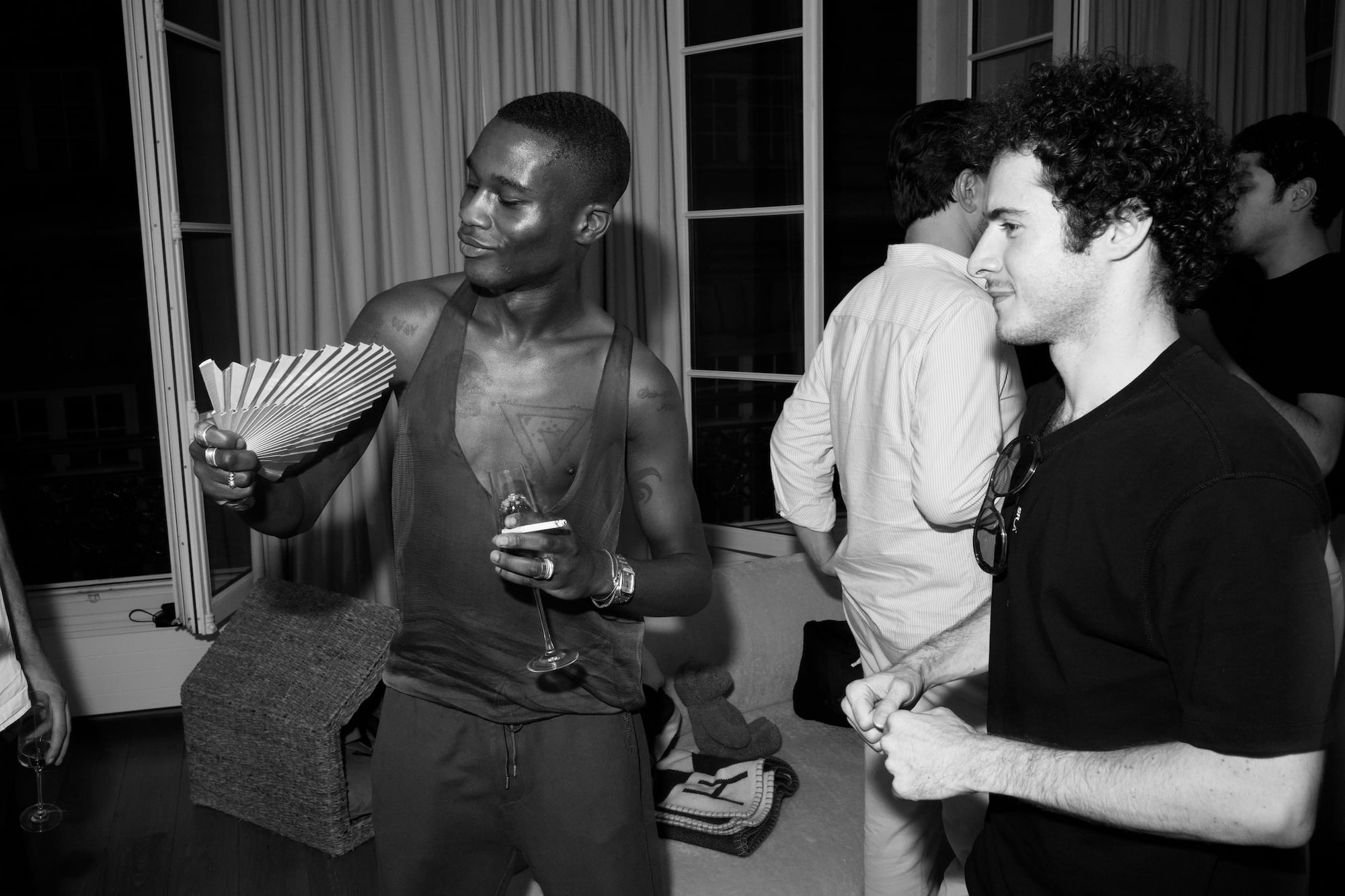 Two guests talking while one cools himself with a folding fan.