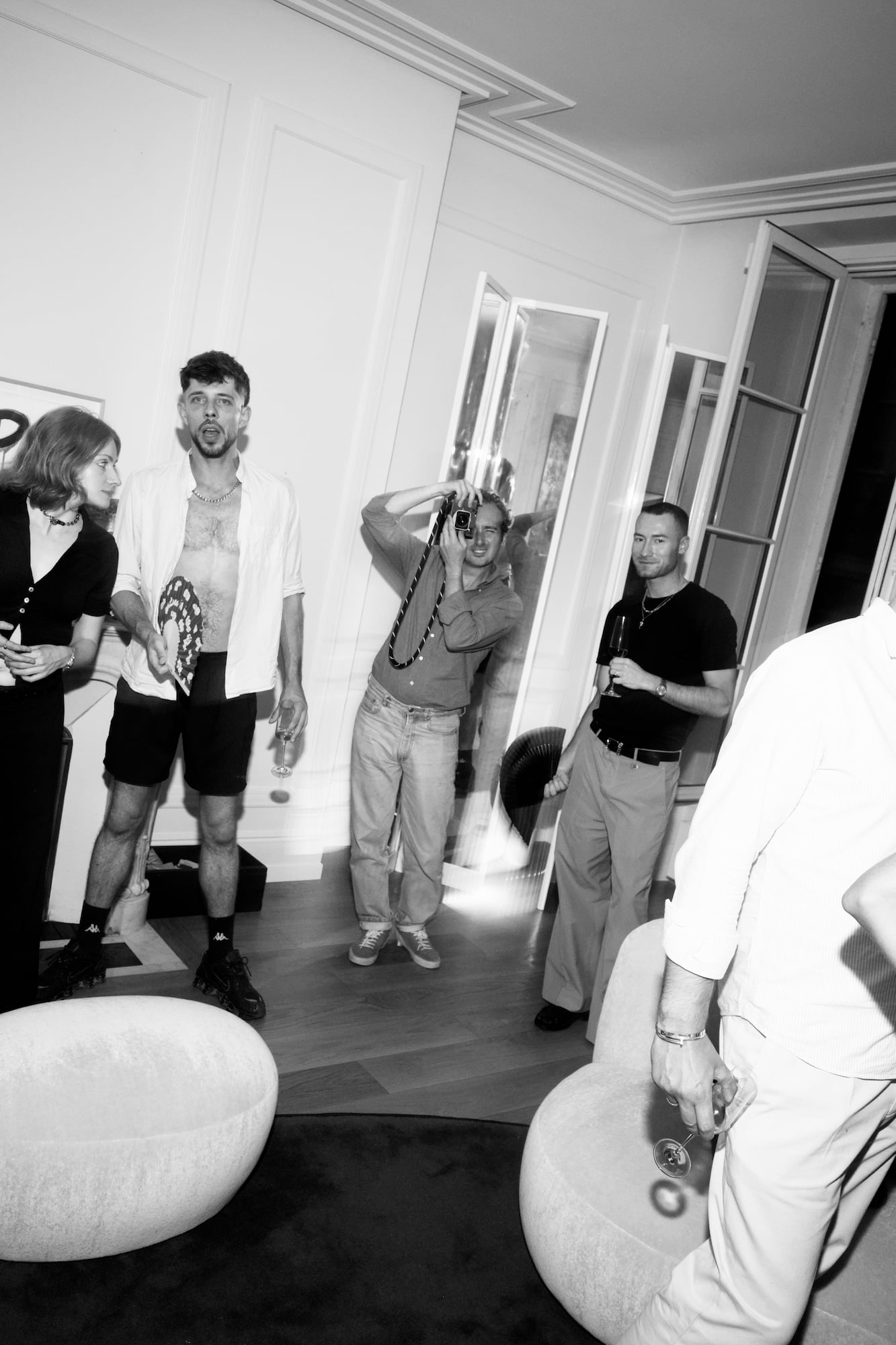 Guests watching the photographer during the gathering in a Paris apartment.