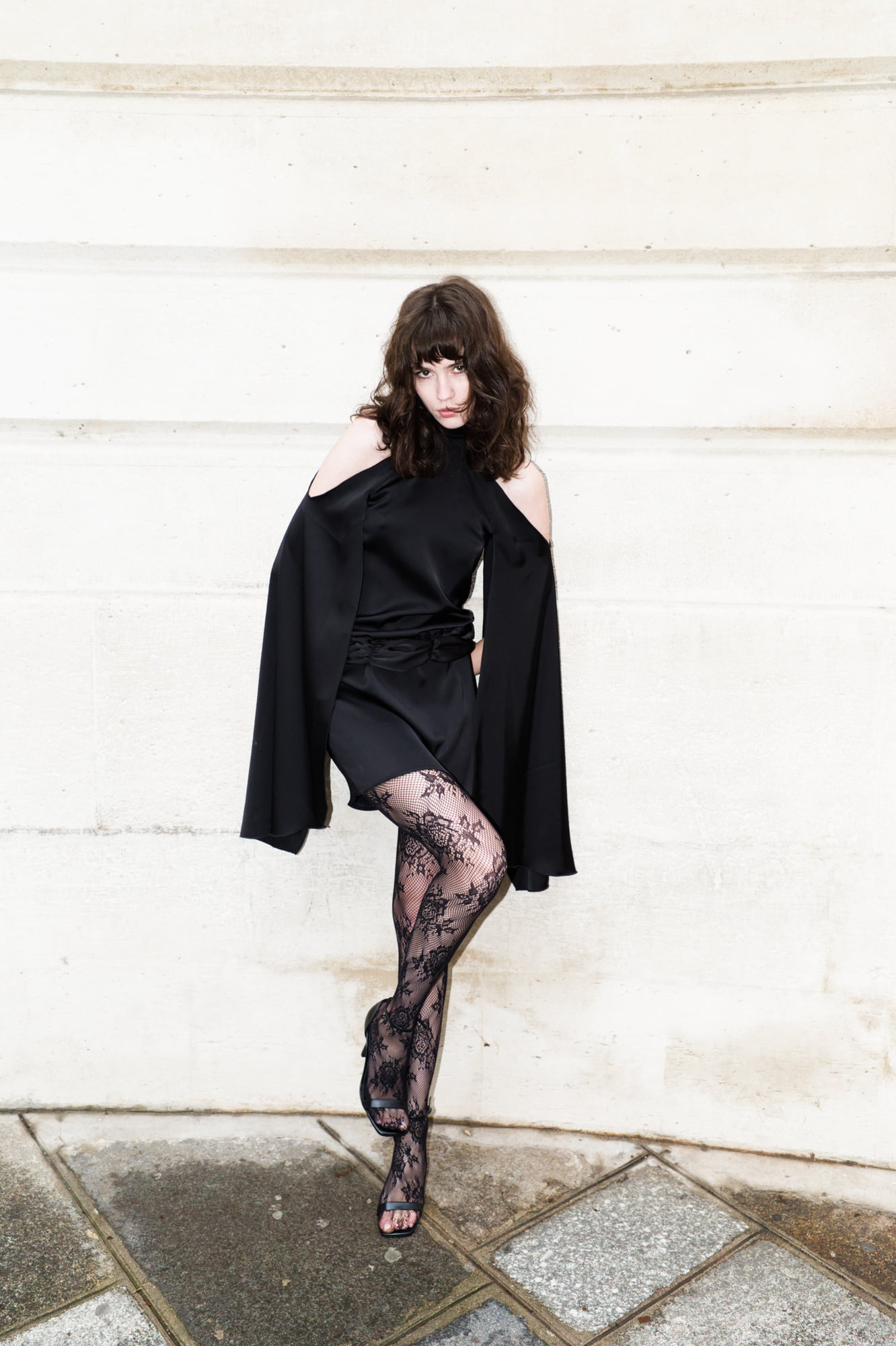 Polly Levin wearing a black BlancBloom AW25 look against a pale stone wall in Paris