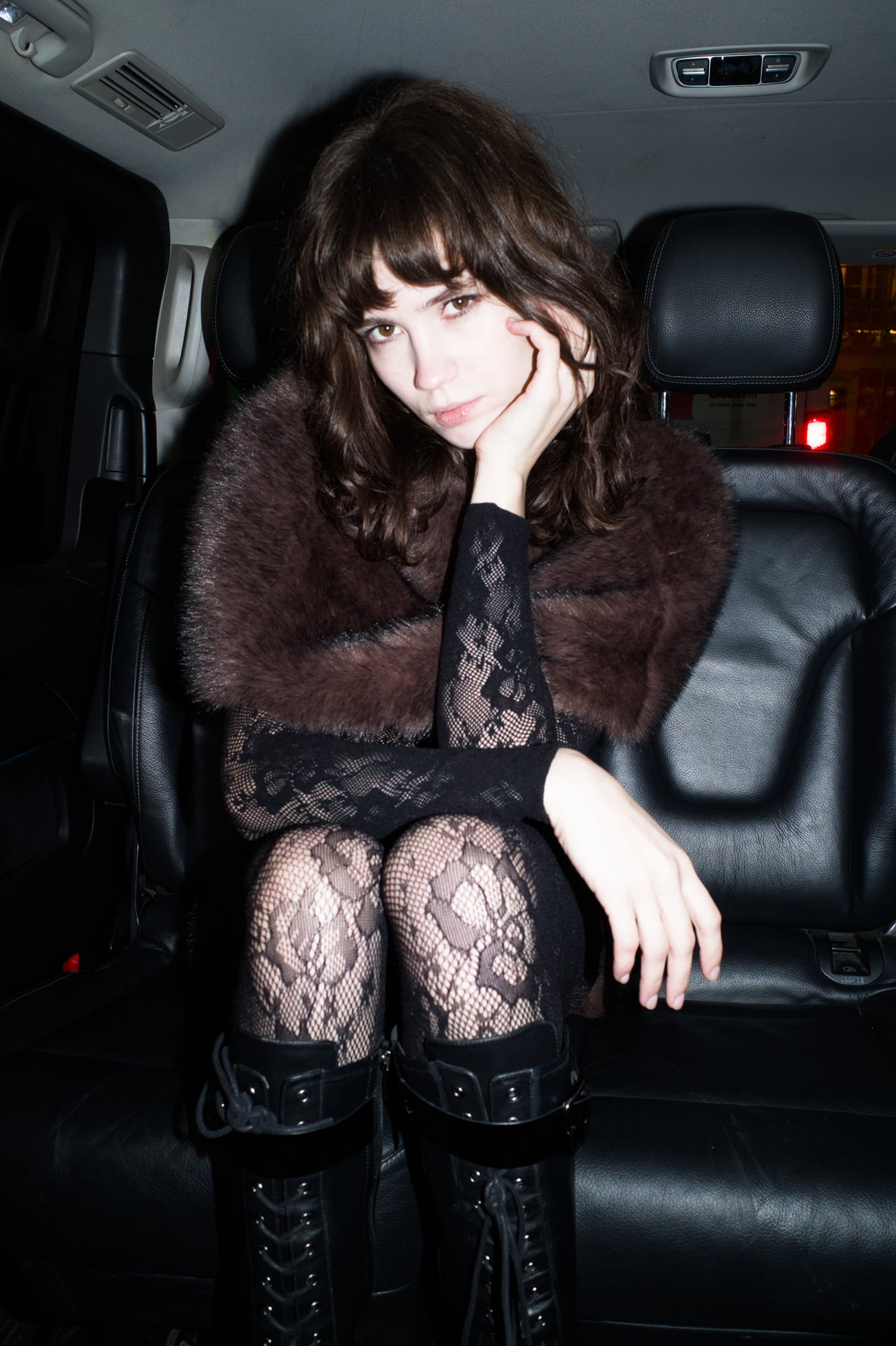 Polly Levin seated in a car wearing lace tights and a faux fur stole for BlancBloom AW25