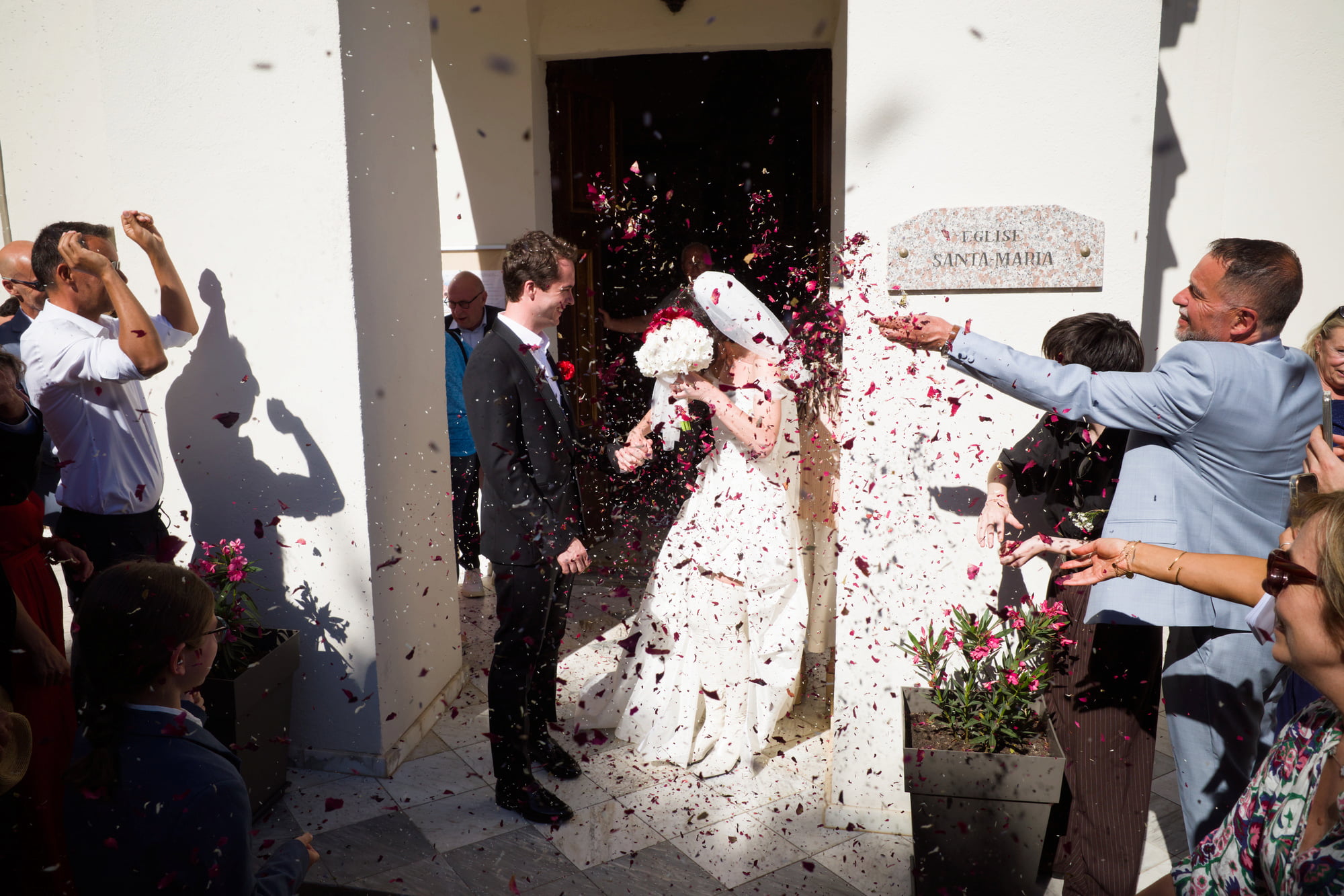 Gabriel and Eléa leaving the church beneath a shower of flower petals.