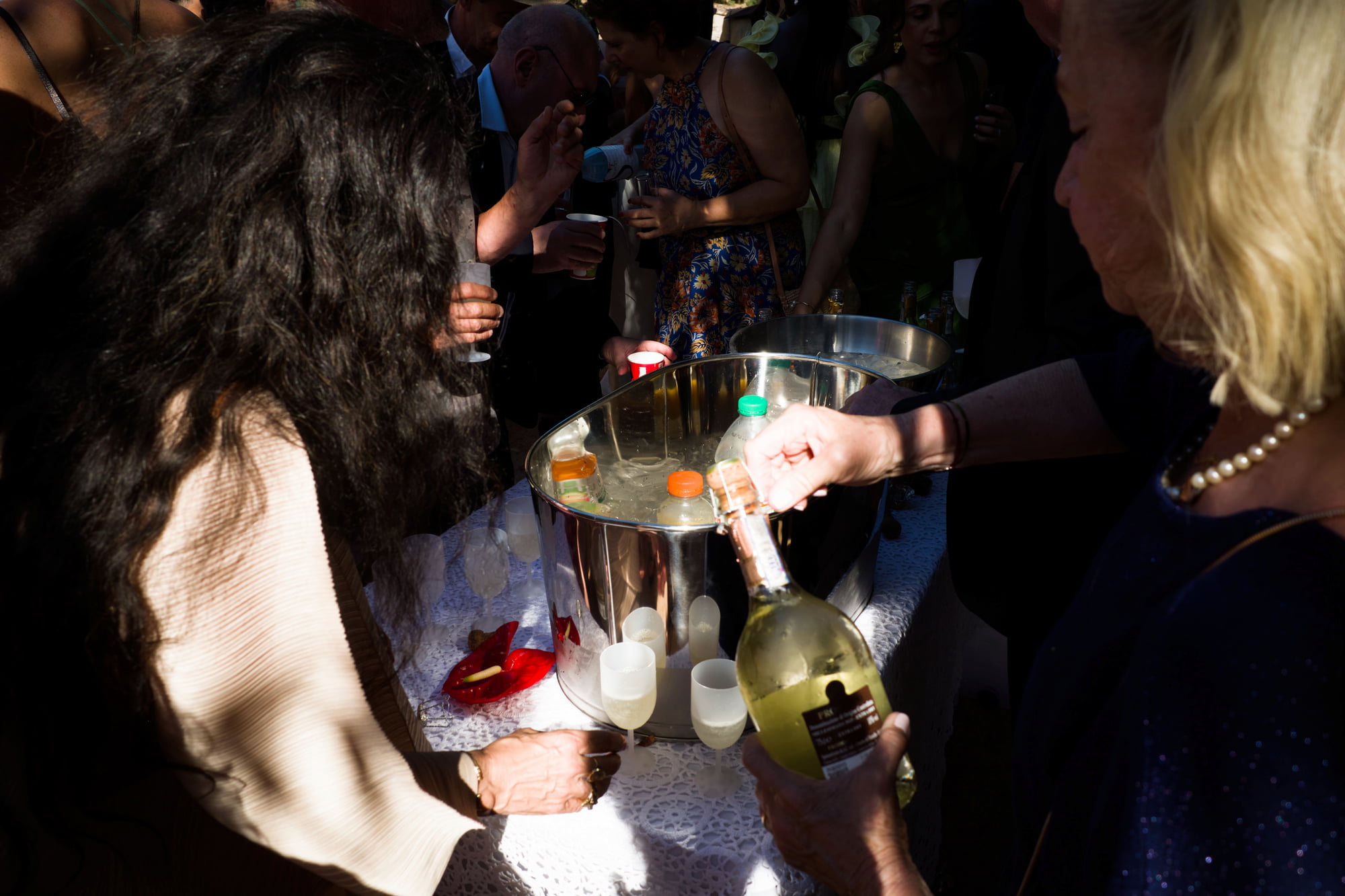 Guests gathered around drinks in the shade during the wedding reception.