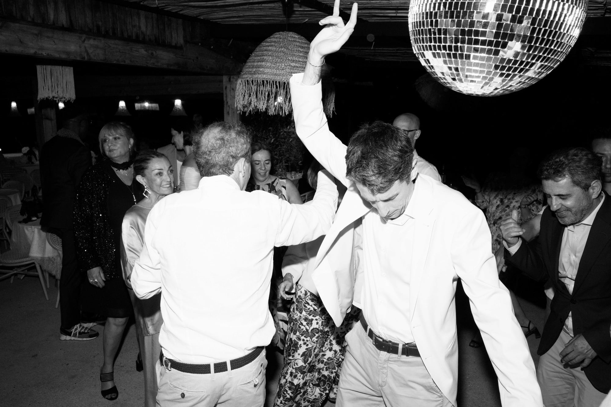 Black-and-white photograph of guests dancing beneath a disco ball.
