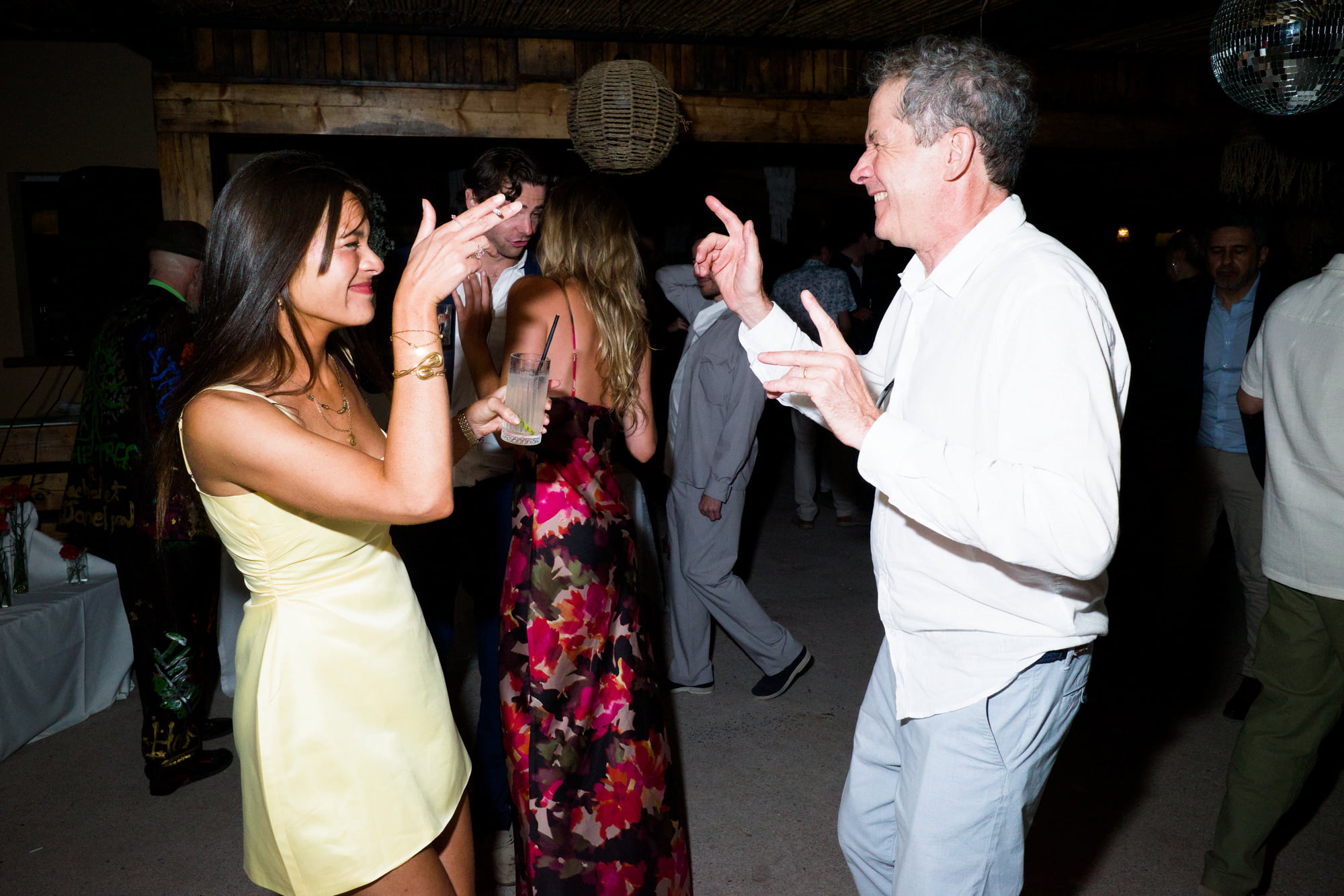 Woman in a pale yellow dress and an older man dancing face to face.