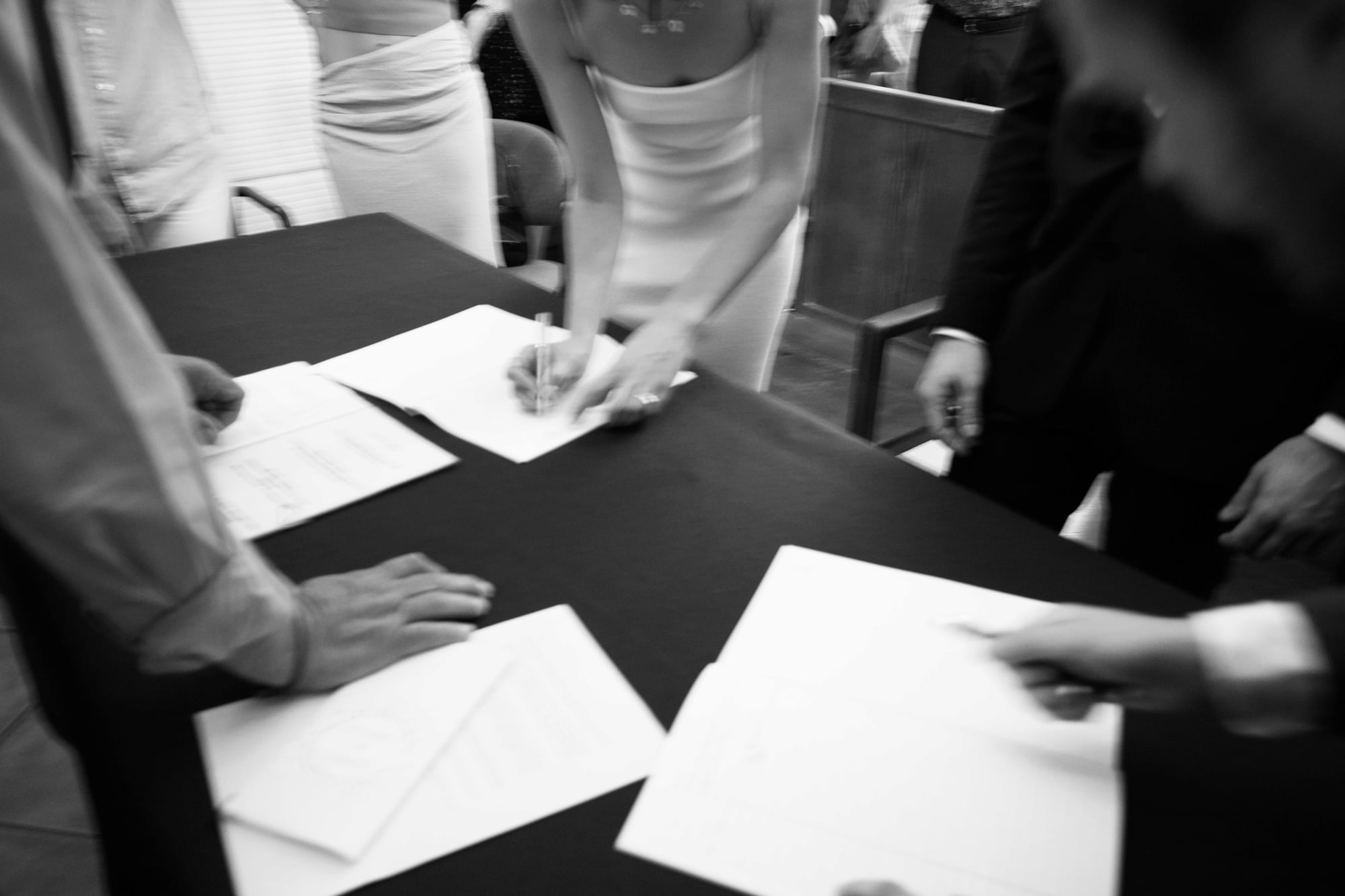 Black-and-white photograph of Eléa signing the marriage register during the ceremony.