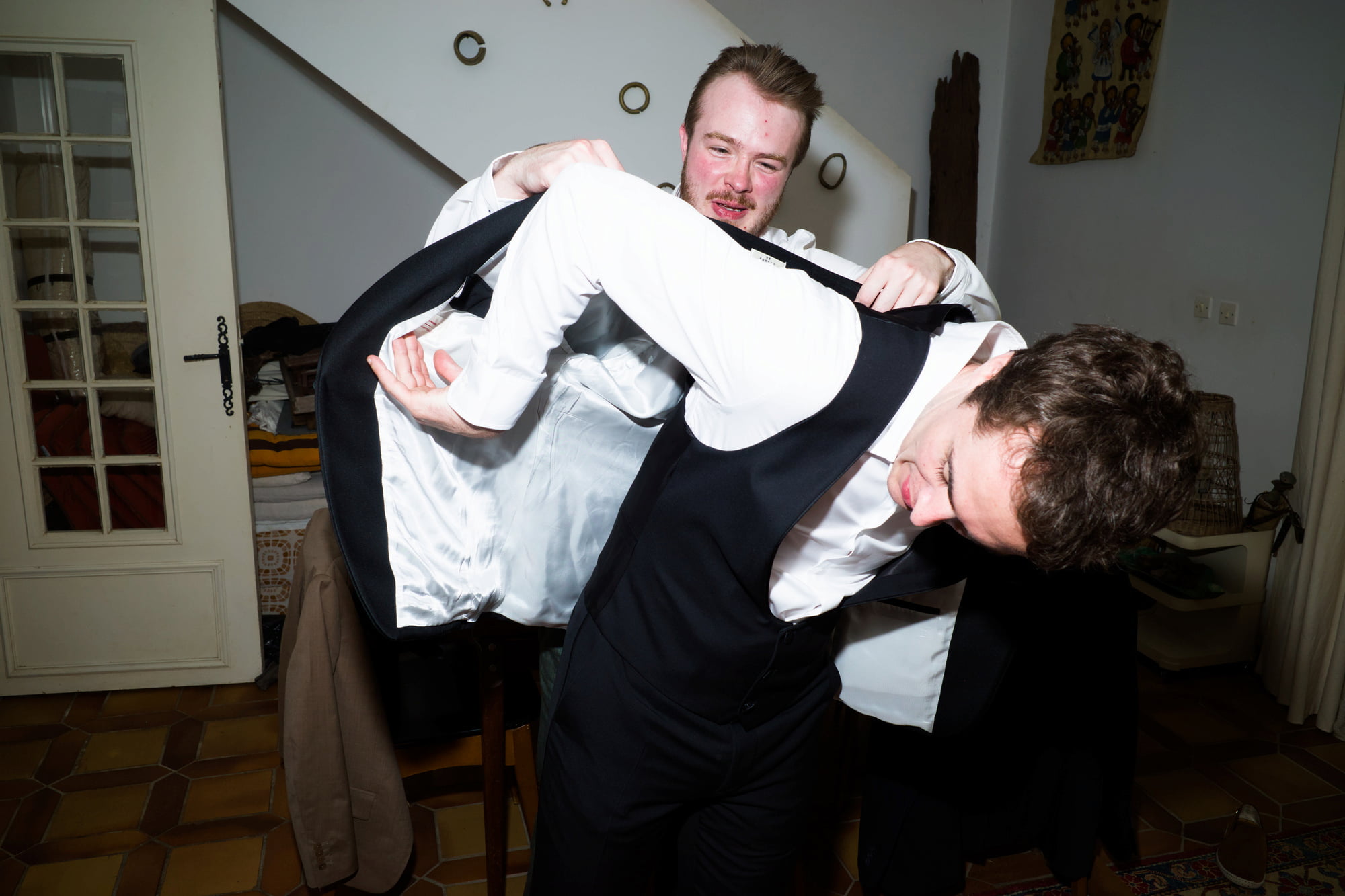 Two men helping Gabriel put on his suit jacket before the wedding.