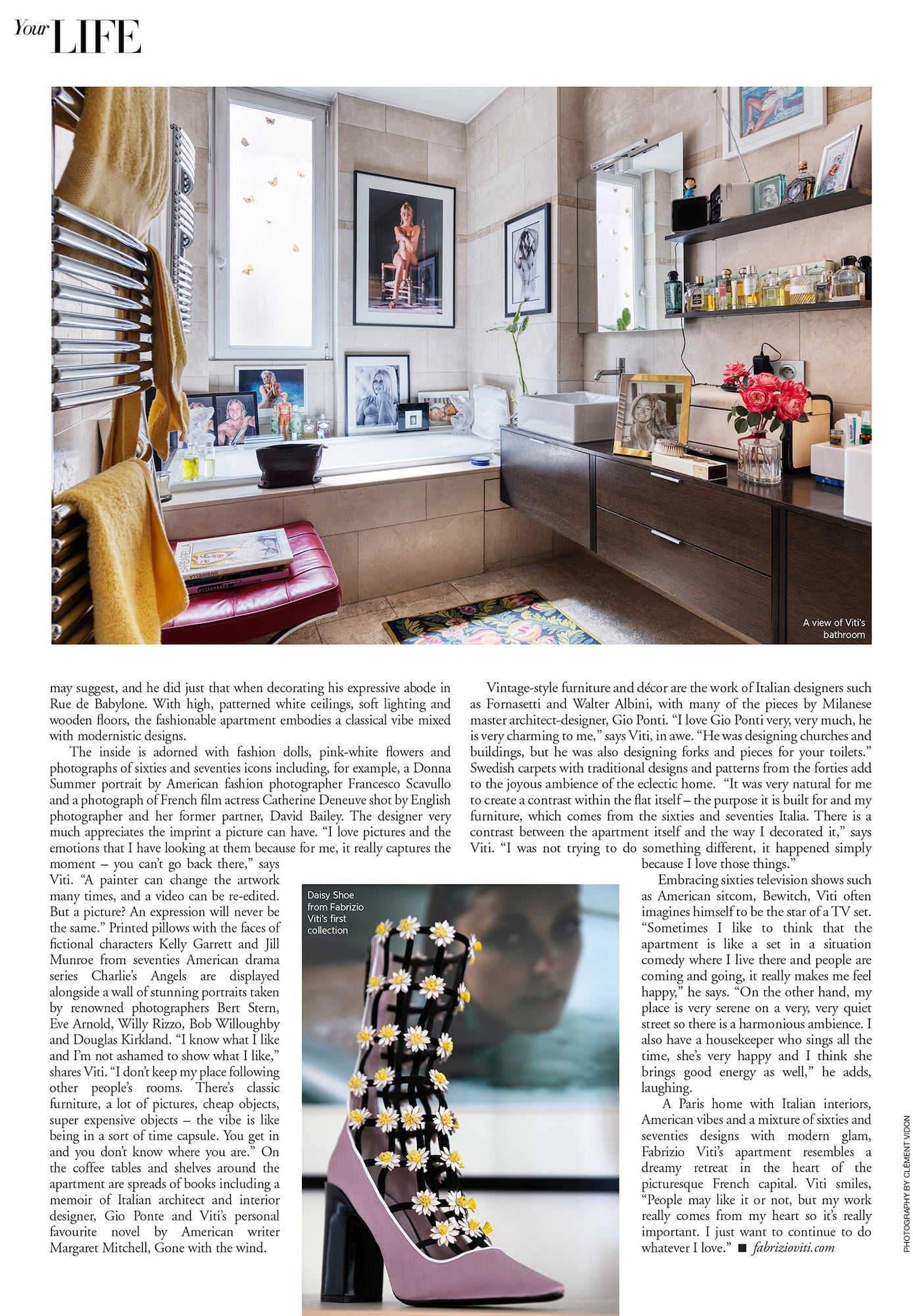 Bathroom in Fabrizio Viti’s Paris apartment with framed photographs, flowers, books, perfume bottles, and a red bench