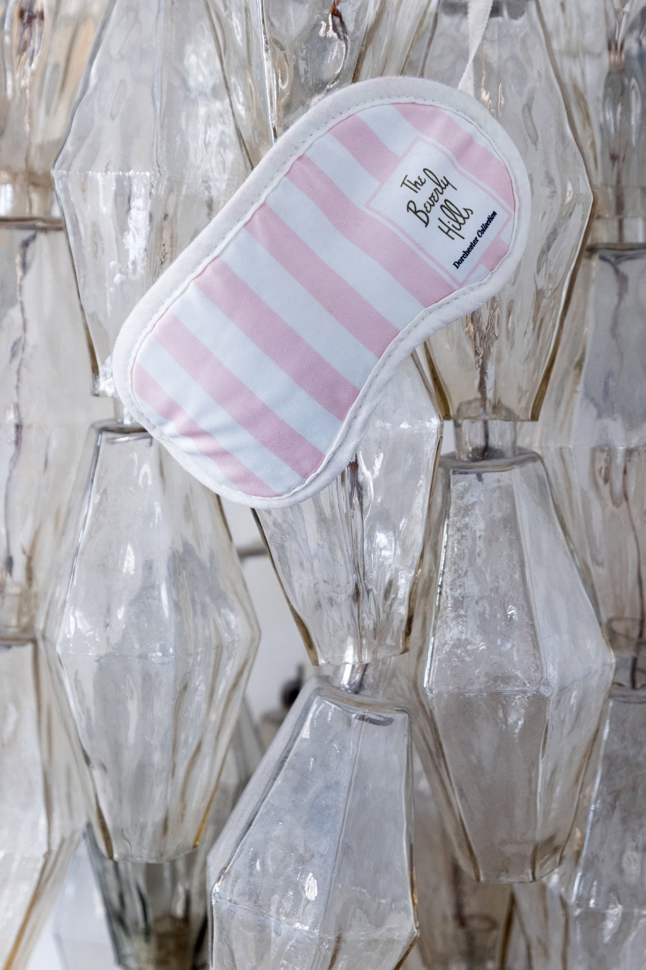 Pink-and-white striped sleep mask displayed on a glass chandelier in Fabrizio Viti’s Paris apartment