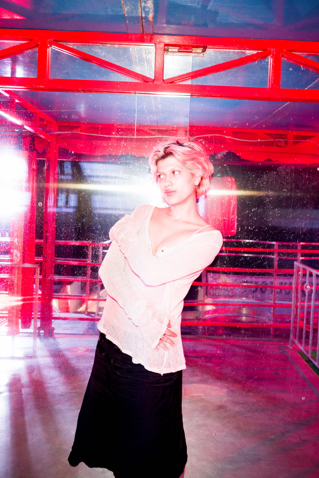 Portrait of Juliette inside a Ferris wheel gondola lit by pink neon lights.