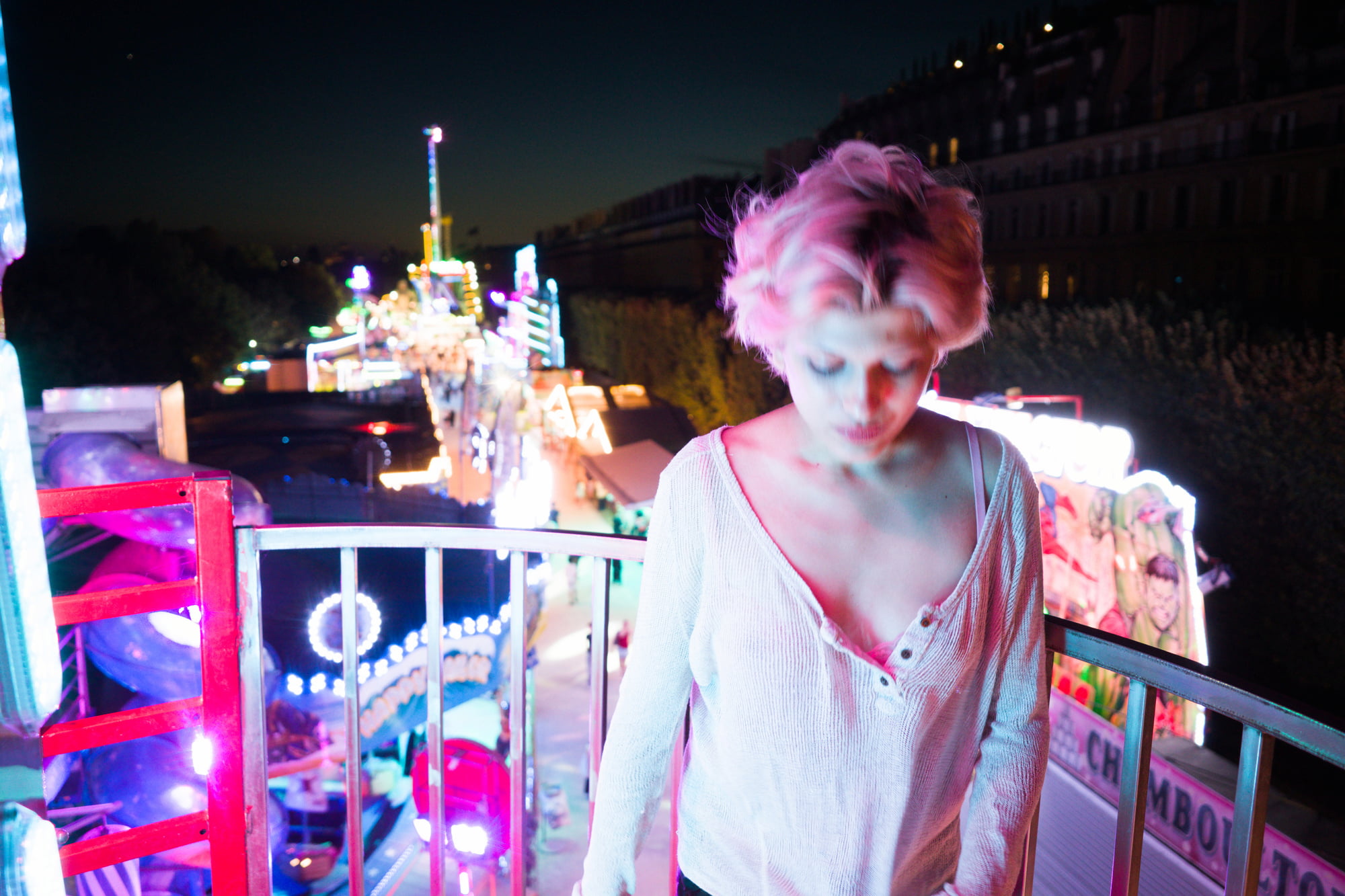 Diptych of Juliette leaning against the railing of a Ferris wheel overlooking the Paris fairgrounds at night.