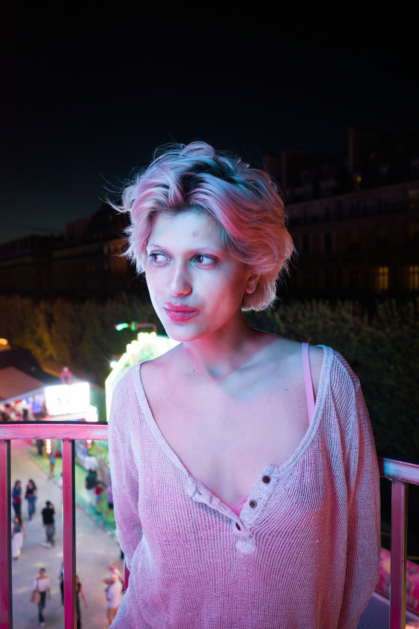 Portrait of Juliette looking away inside a Ferris wheel gondola above the Paris fairgrounds at night.