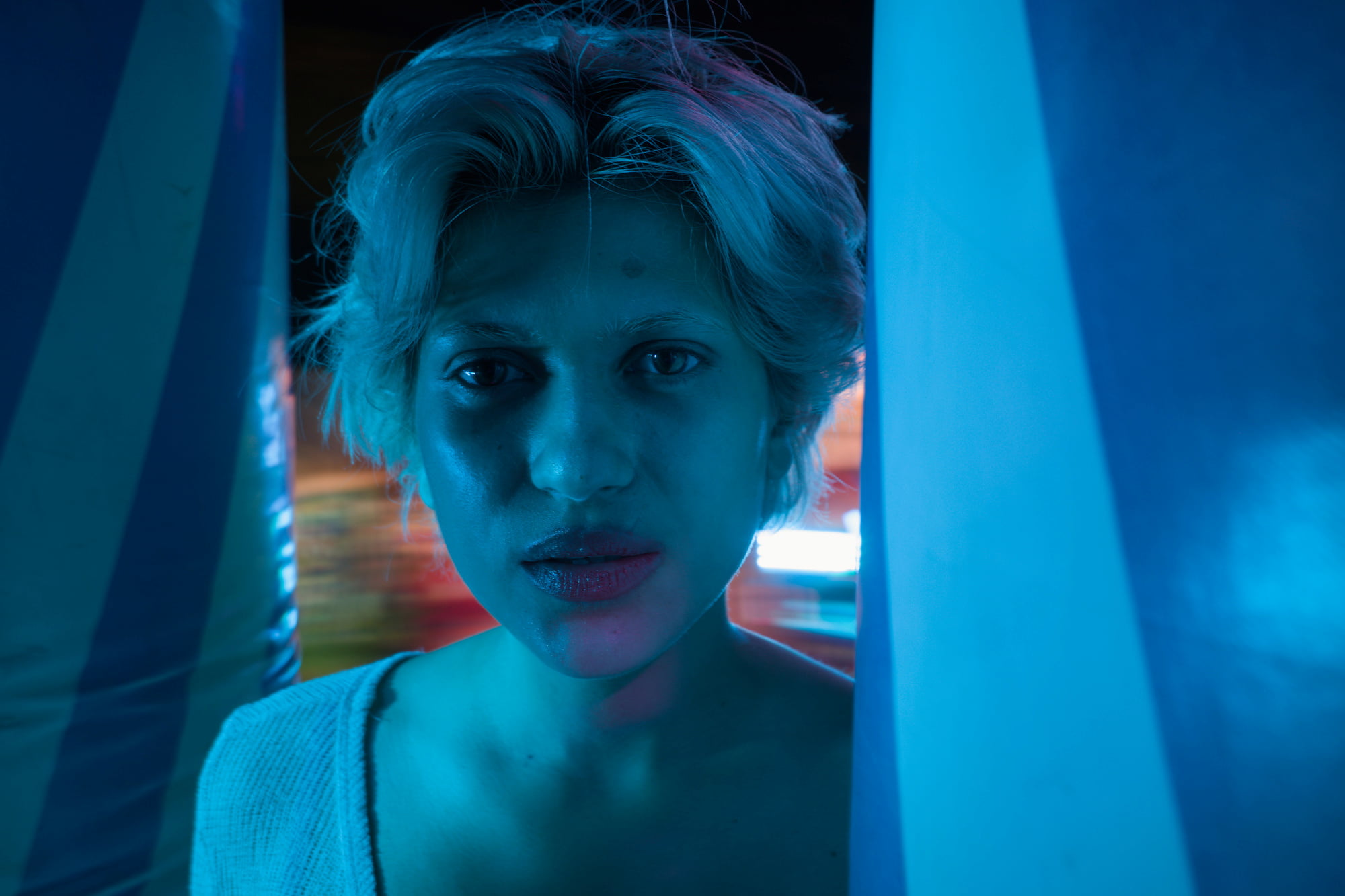 Close portrait of Juliette illuminated by blue light inside a fairground attraction.