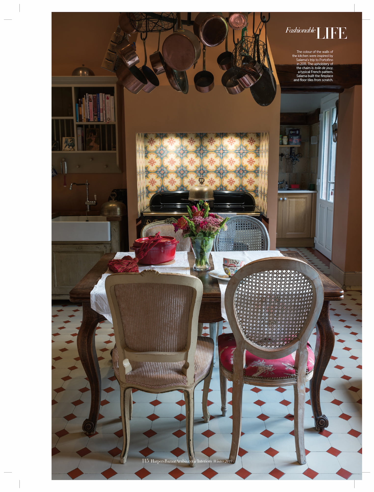 Kitchen in Salama Khalfan’s French country house with patterned tiles, copper pans, cane chairs, and a wooden table