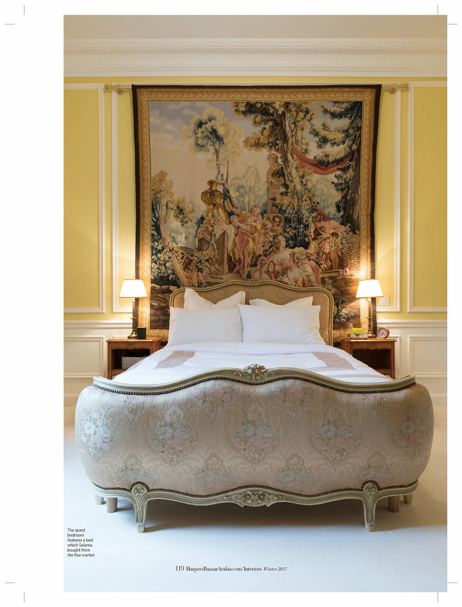 Guest bedroom in Salama Khalfan’s country house with an antique bed, yellow walls, and a large tapestry
