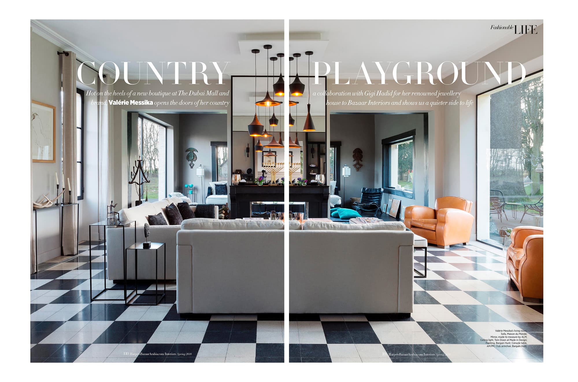 Living room at Valérie Messika’s country house with a white sofa, orange leather armchairs, black-and-white tiled floor, and large windows