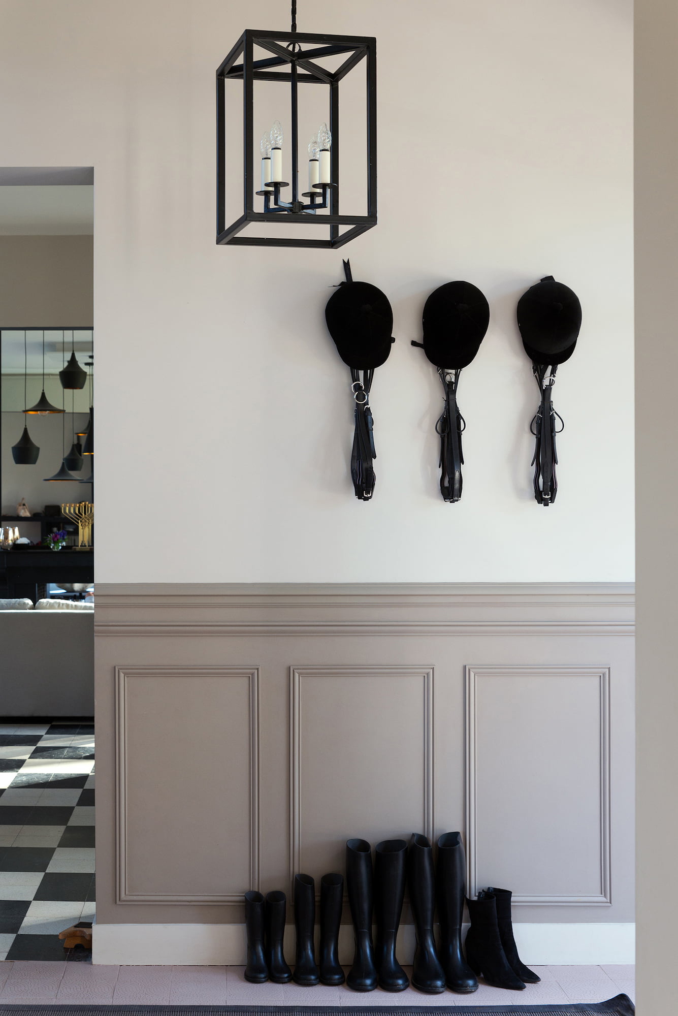 Equestrian helmets, bridles, and riding boots displayed in the entrance of Valérie Messika’s country house