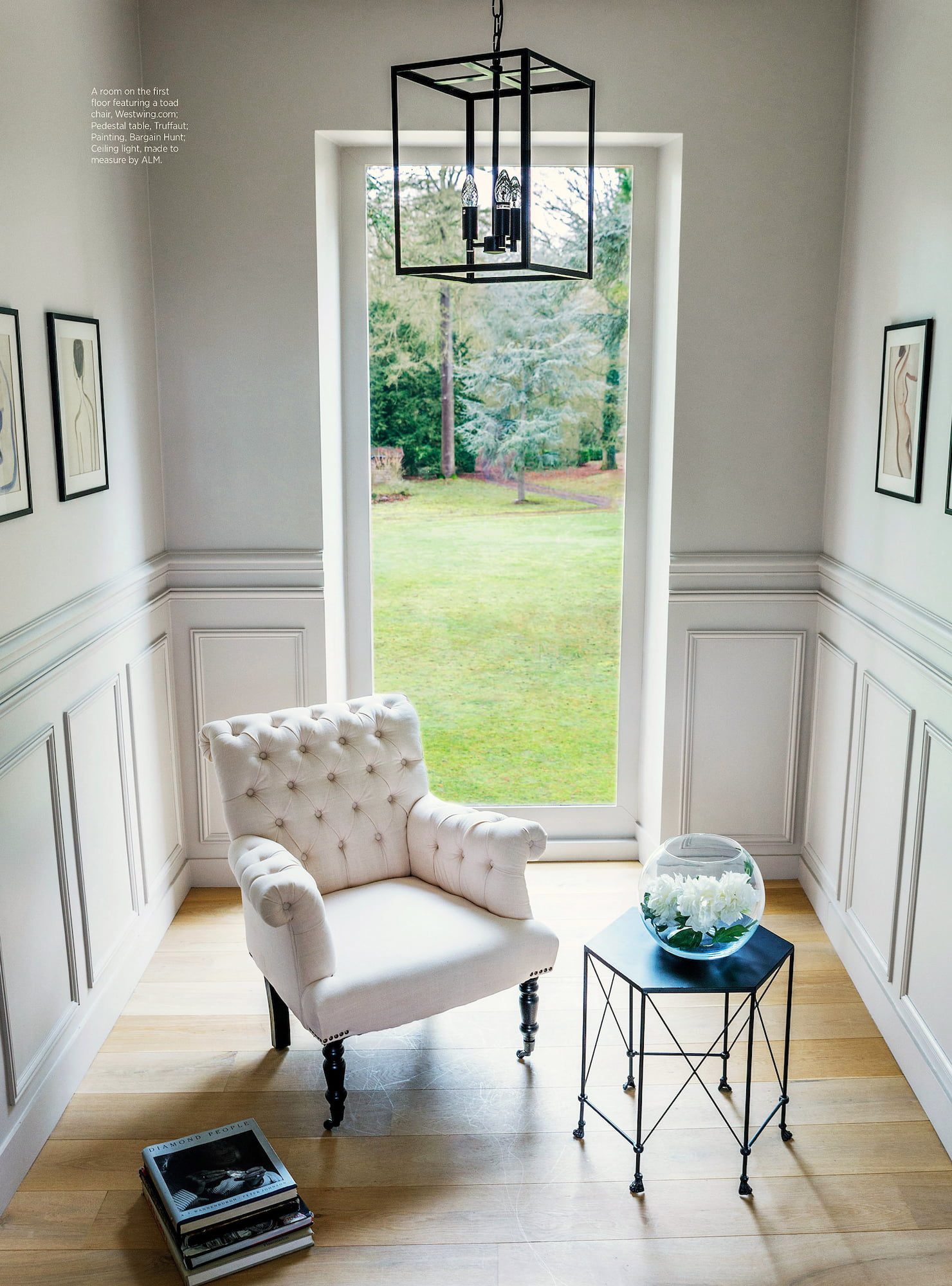 White tufted armchair and black pedestal table facing a large window at Valérie Messika’s country house