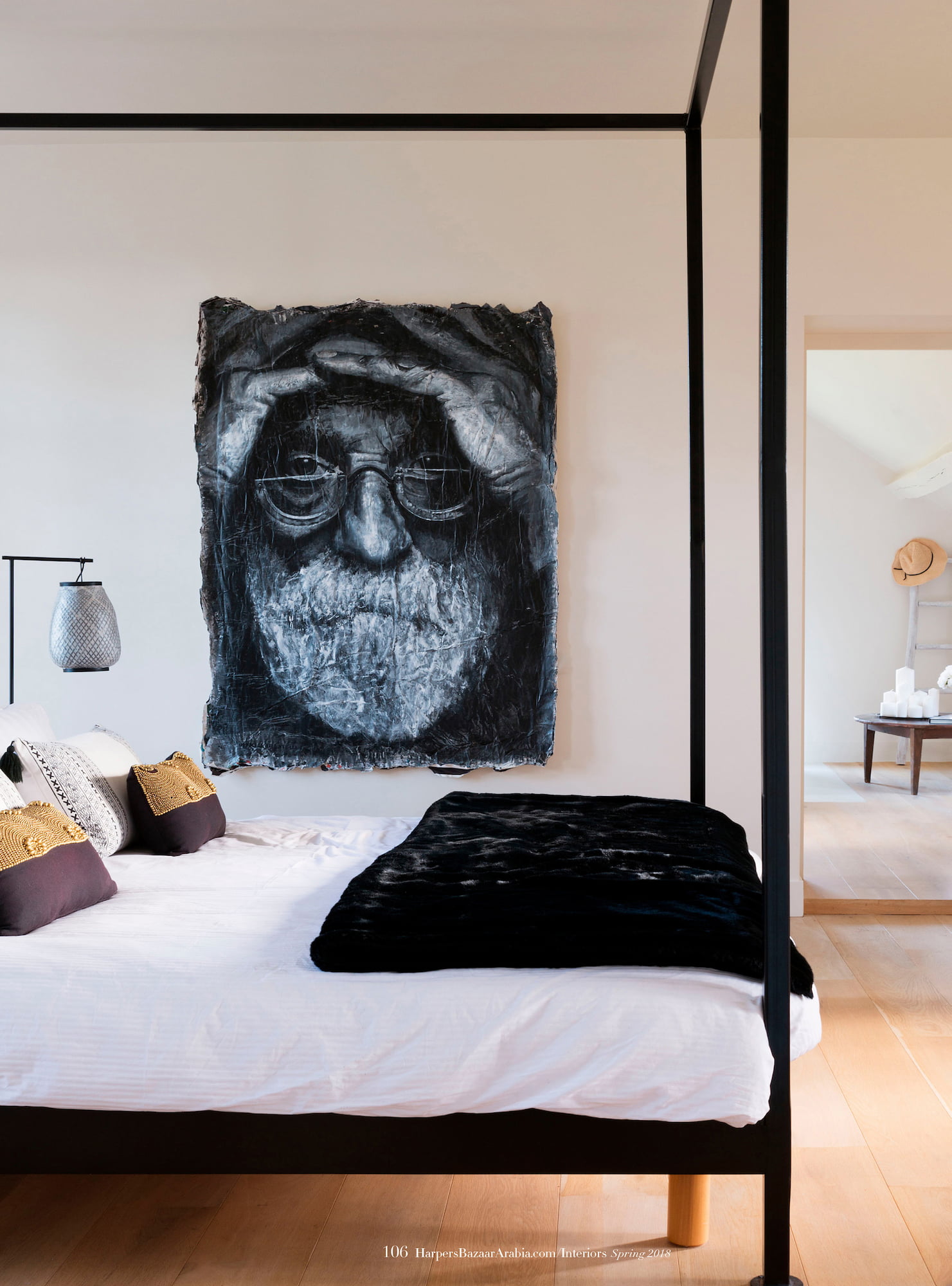 Bedroom at Valérie Messika’s country house with a black canopy bed, black-and-white portrait artwork, and pale wooden floor
