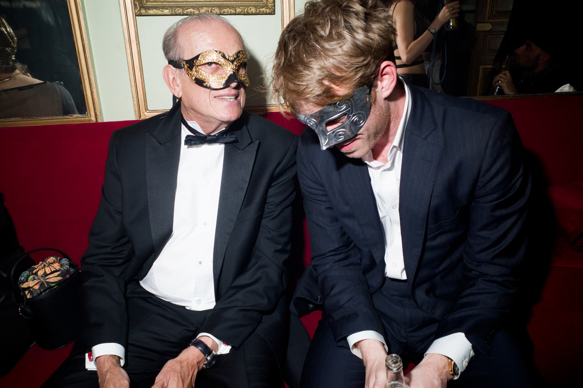 Elegant masked men seated at soirée